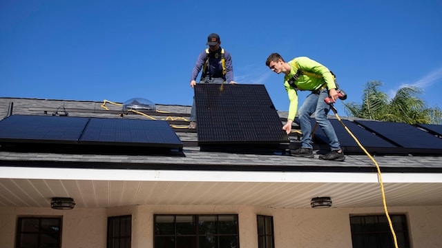 People installing solar panels on roof