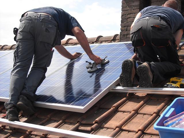 People mounting solar panels on roof